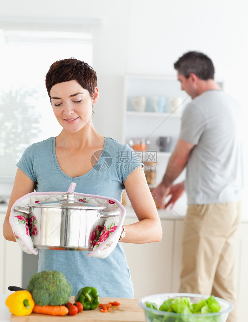 可爱的妻子拿着锅 而她的丈夫正在洗碗图片