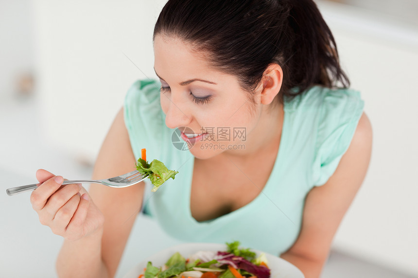 美丽的年轻女孩吃沙拉图片