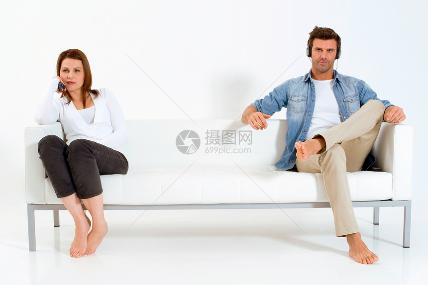 在沙发上看电视的分居夫妇成年人男人异性恋赤脚异性日常生活耳机同居牛仔裤女士图片