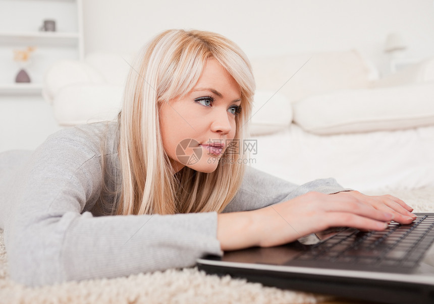 美丽的集中女性 躺在雕刻上的笔记本电脑上放松图片