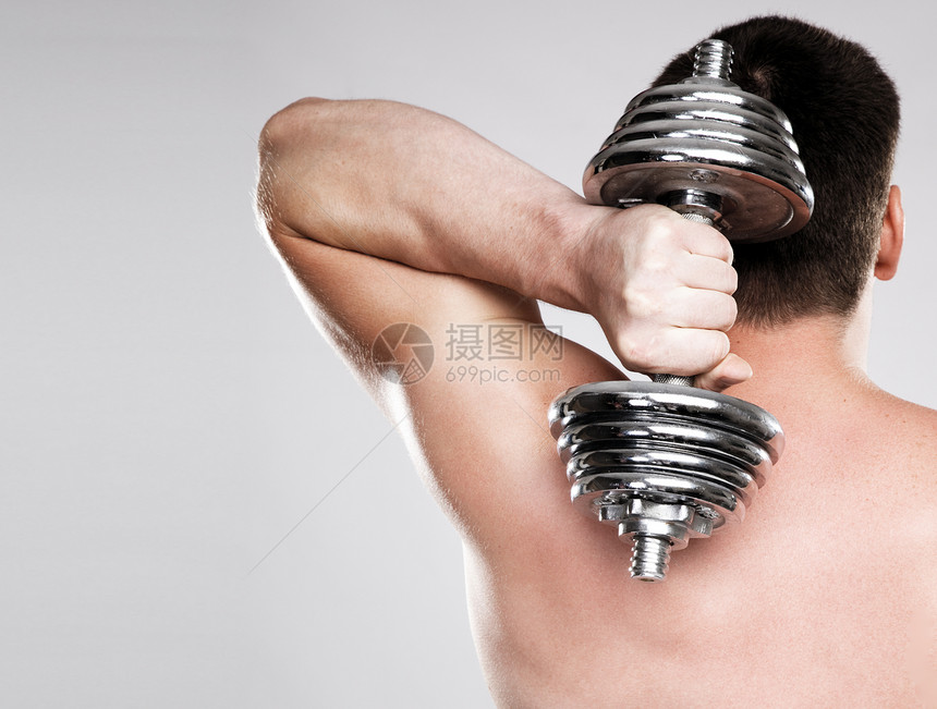 抬起一个哑铃的运动健壮人健身房男性白色肌肉训练运动员膀子健美男人工作室图片