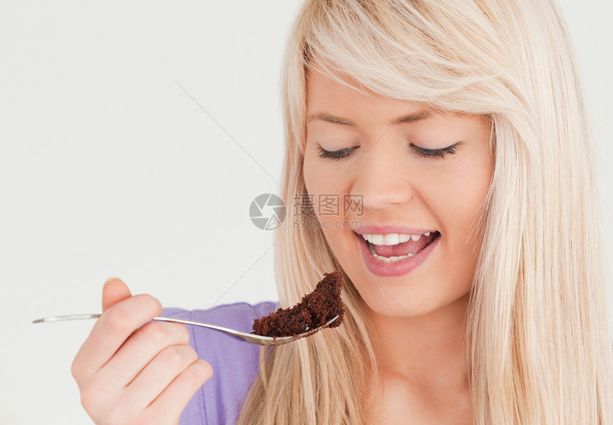 美女金发女人吃蛋糕的肖像图片