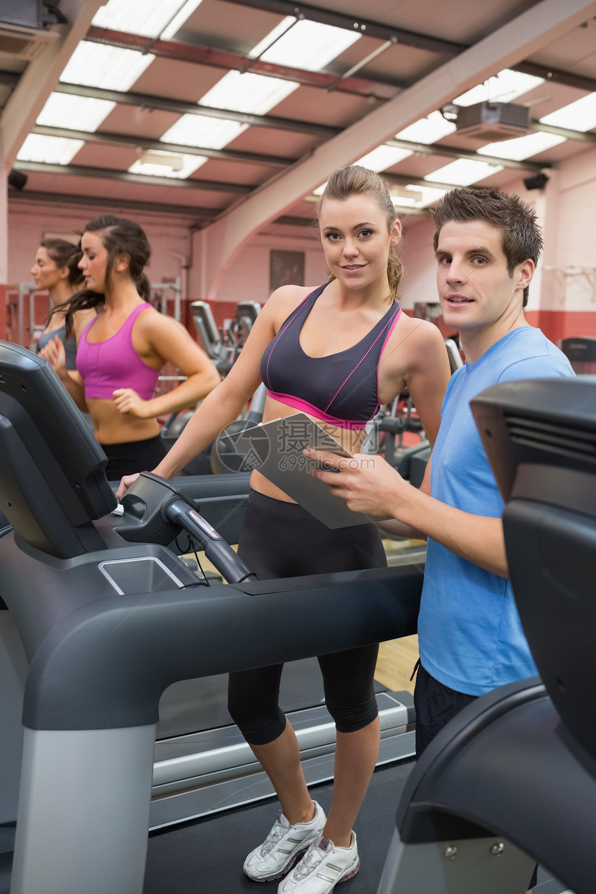 教官和健身房里的女人女士男性男人活动瘦身指导身体机器训练跑步机图片