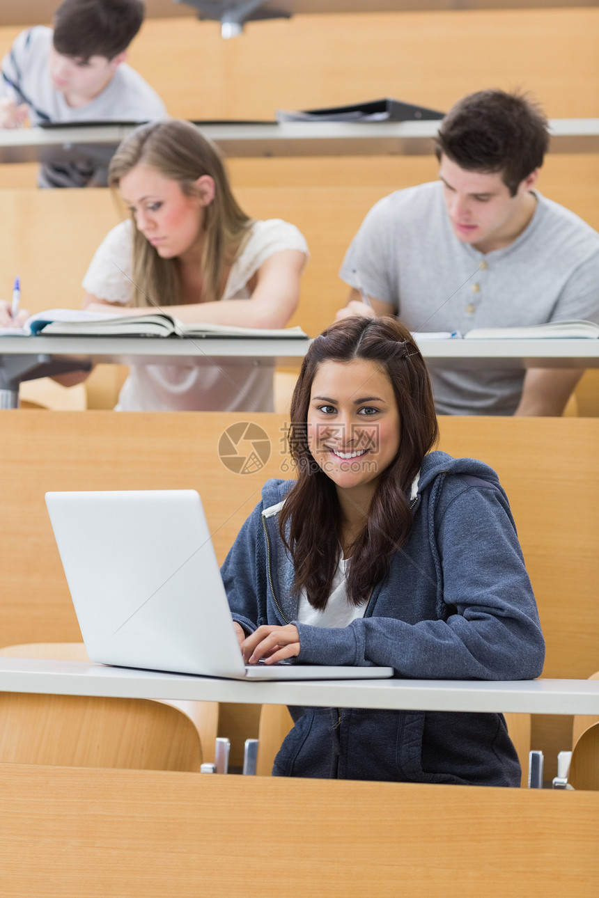 用笔记本电脑讲课时微笑的学生图片