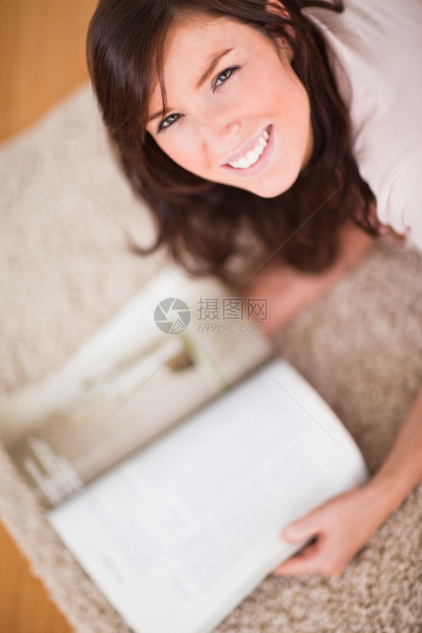 躺在地毯上时看杂志的可爱女郎图片