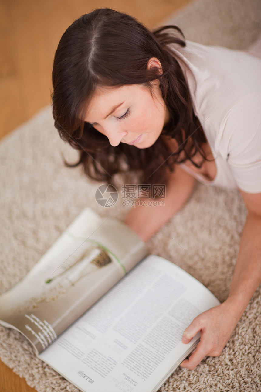 可爱的女子躺在地毯上看杂志 却在看杂志图片