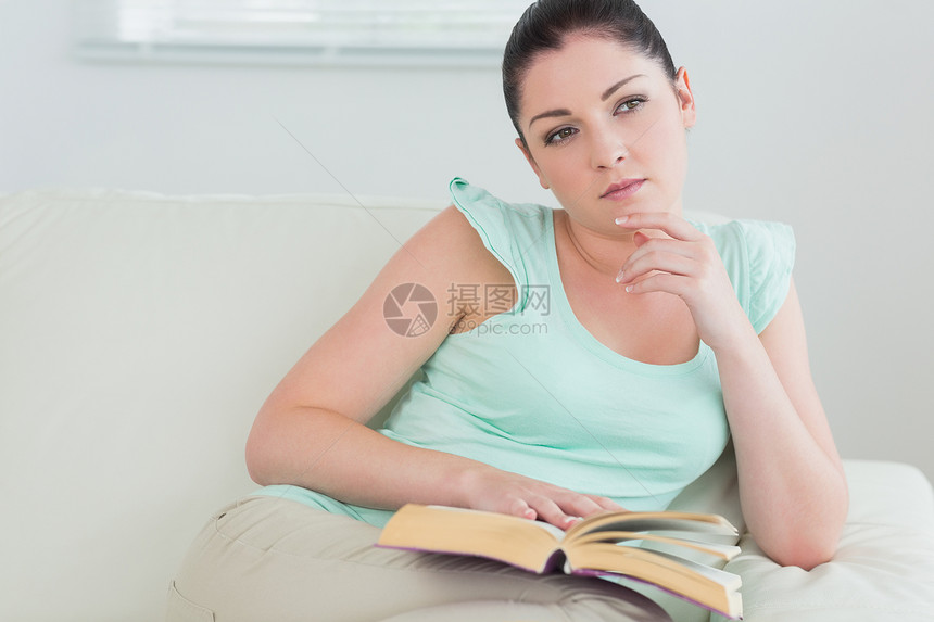 在沙发上读书的 深思熟虑的女人图片