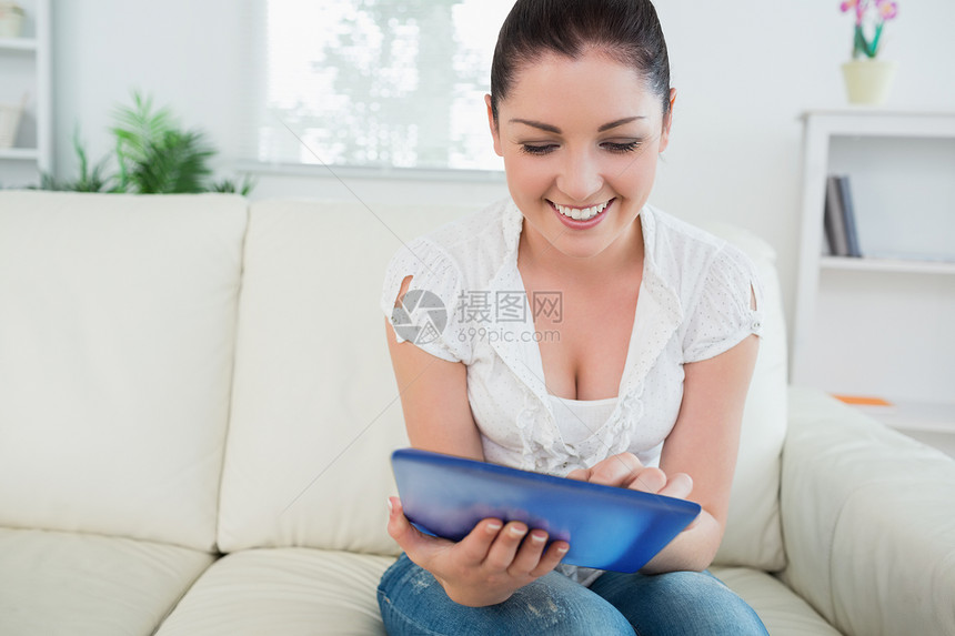笑女人用沙发上的平板电脑图片