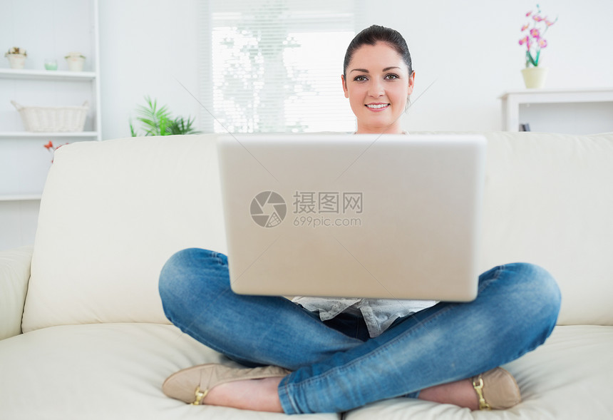 妇女用笔记本电脑坐在沙发上休息室公寓客厅空闲长椅时间窗户技术微笑女士图片