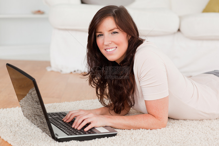 漂亮的黑褐色女人在用笔记本电脑放松图片