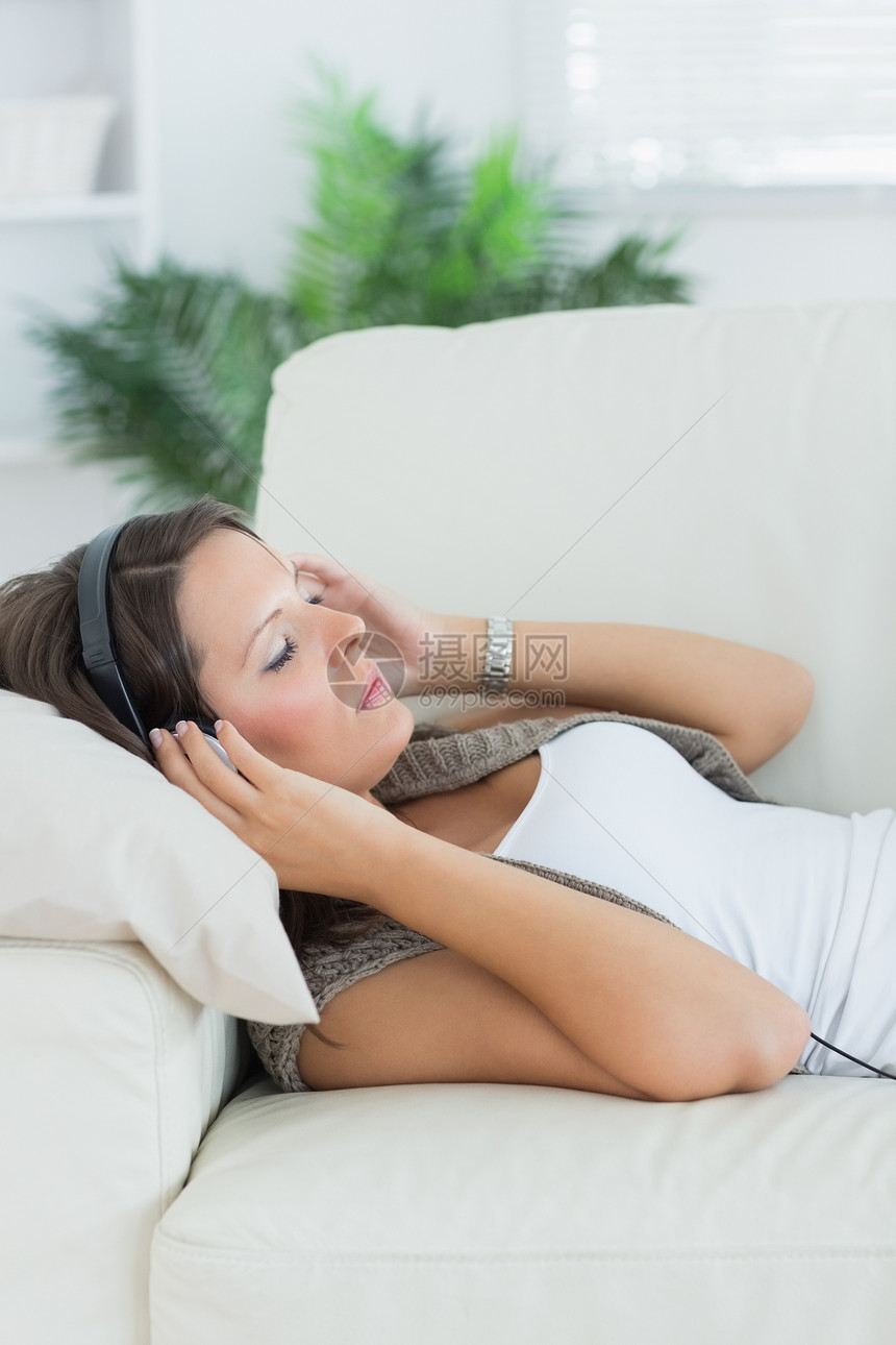 躺在沙发和听音乐上的放松的女人图片