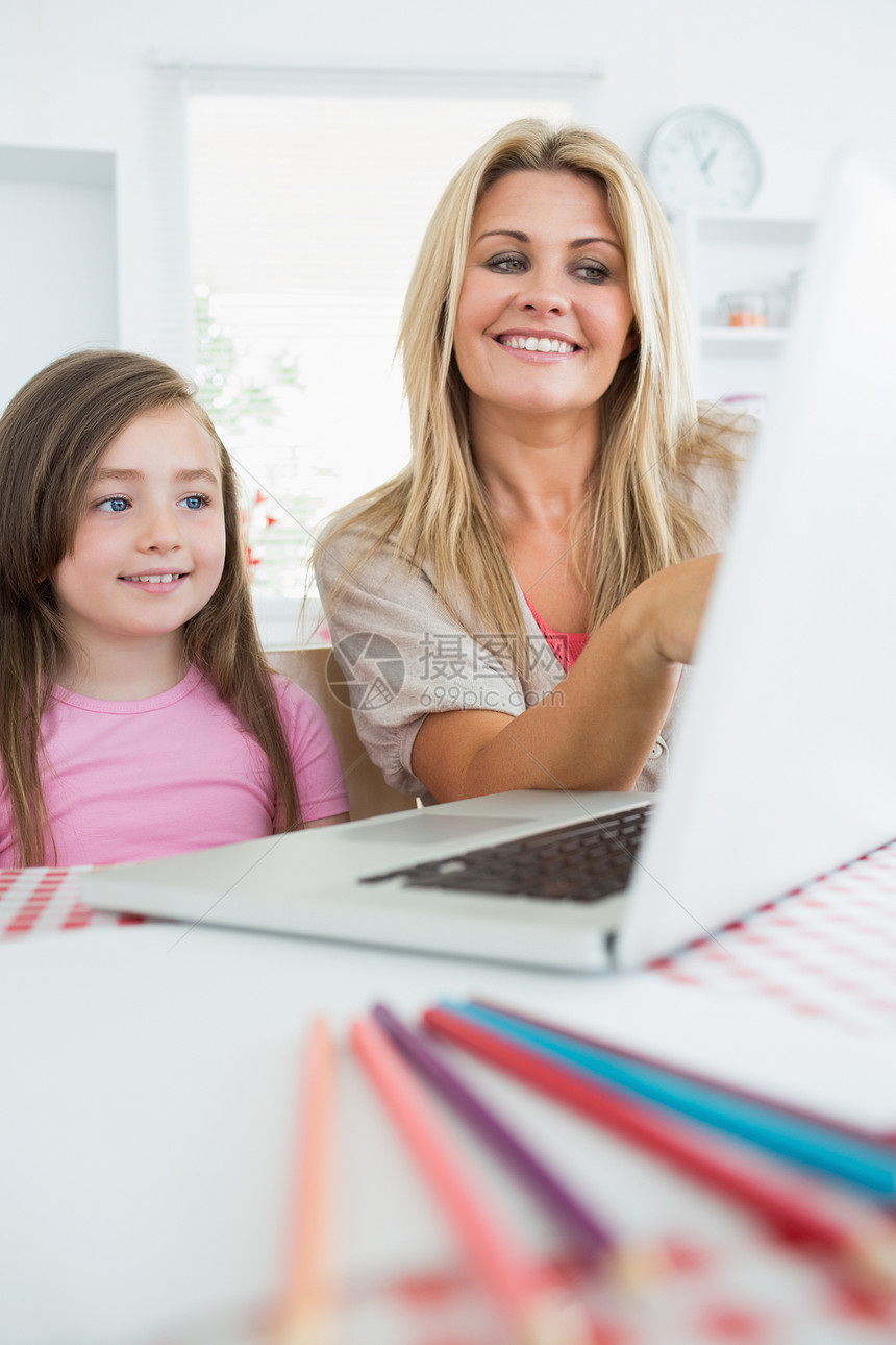 母亲和女儿在笔记本电脑上微笑图片