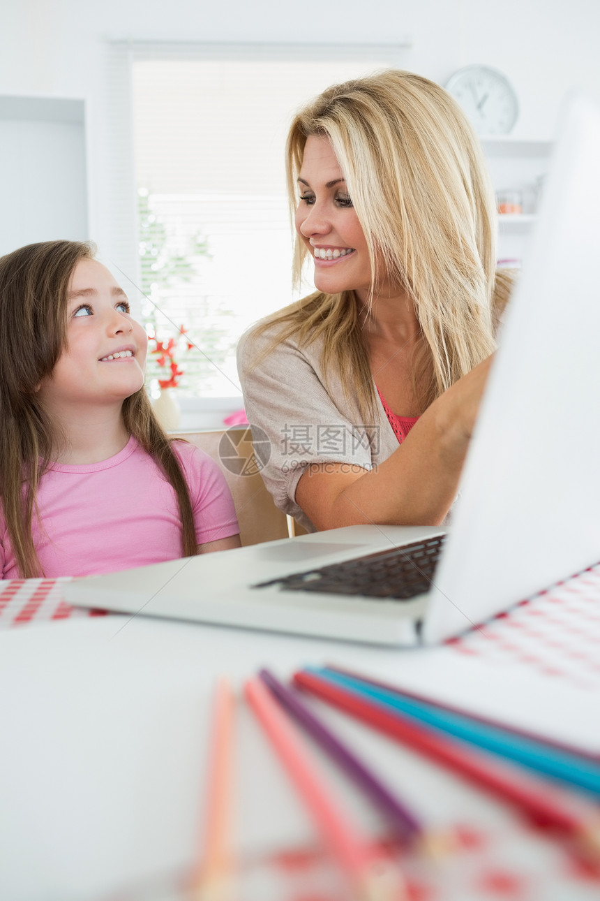 妇女用笔记本电脑微笑着她的女儿图片