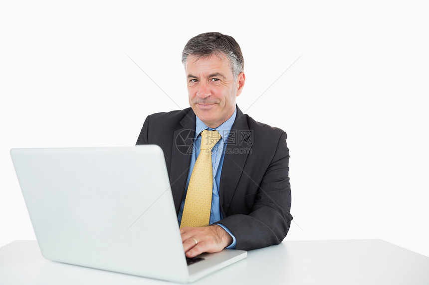 微笑的人在他的笔记本电脑上写作图片
