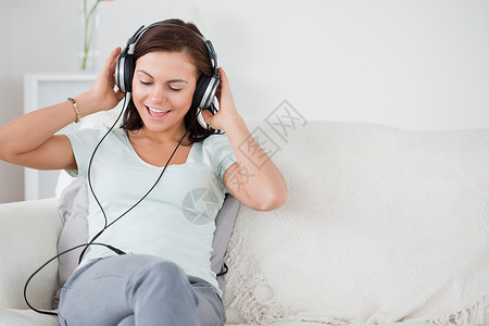 迷人的黑发 听音乐房间音乐播放器青年女性音乐享受女士快乐乐趣长椅背景图片