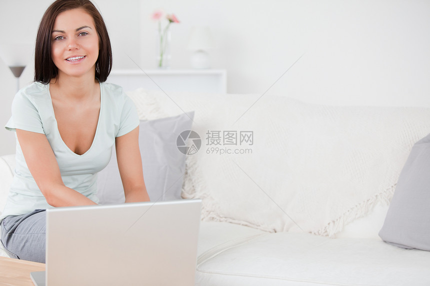 年轻妇女在笔记本电脑上打字沙发互联网学生成人女士黑发女孩房子房间快乐图片