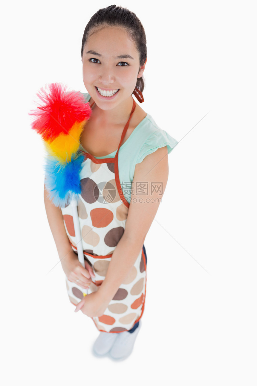 快乐的女士拿着粉尘机微笑家务围裙女性黑眼睛清洁工混血除尘器掸子头发图片