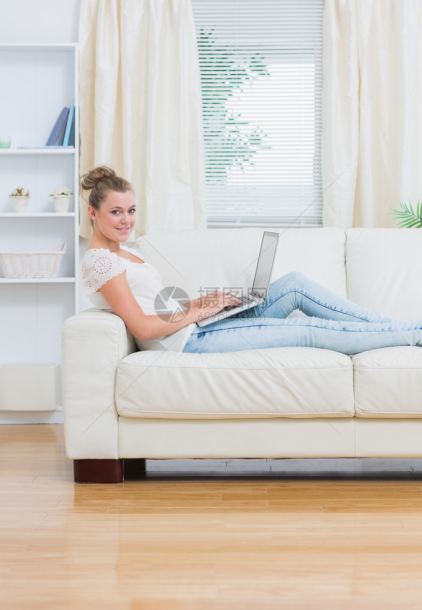 妇女用笔记本电脑躺在沙发上架子女性女士枕头头发客厅技术休息室植物快乐图片