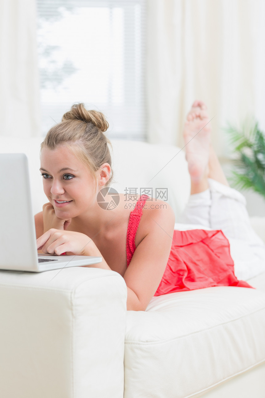 在沙发上用笔记本电脑微笑的女人图片