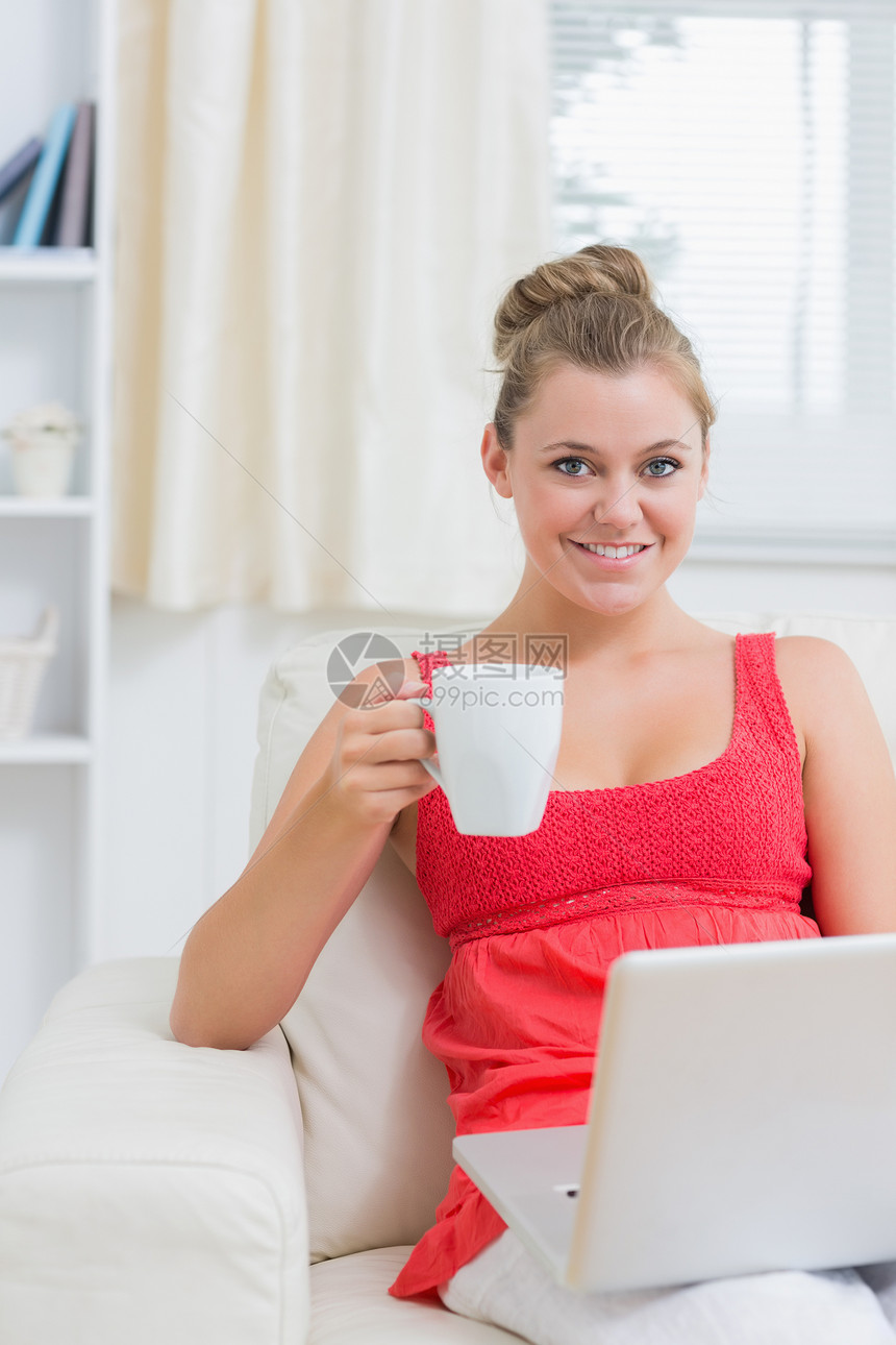 妇女打笔记本电脑时喝咖啡图片