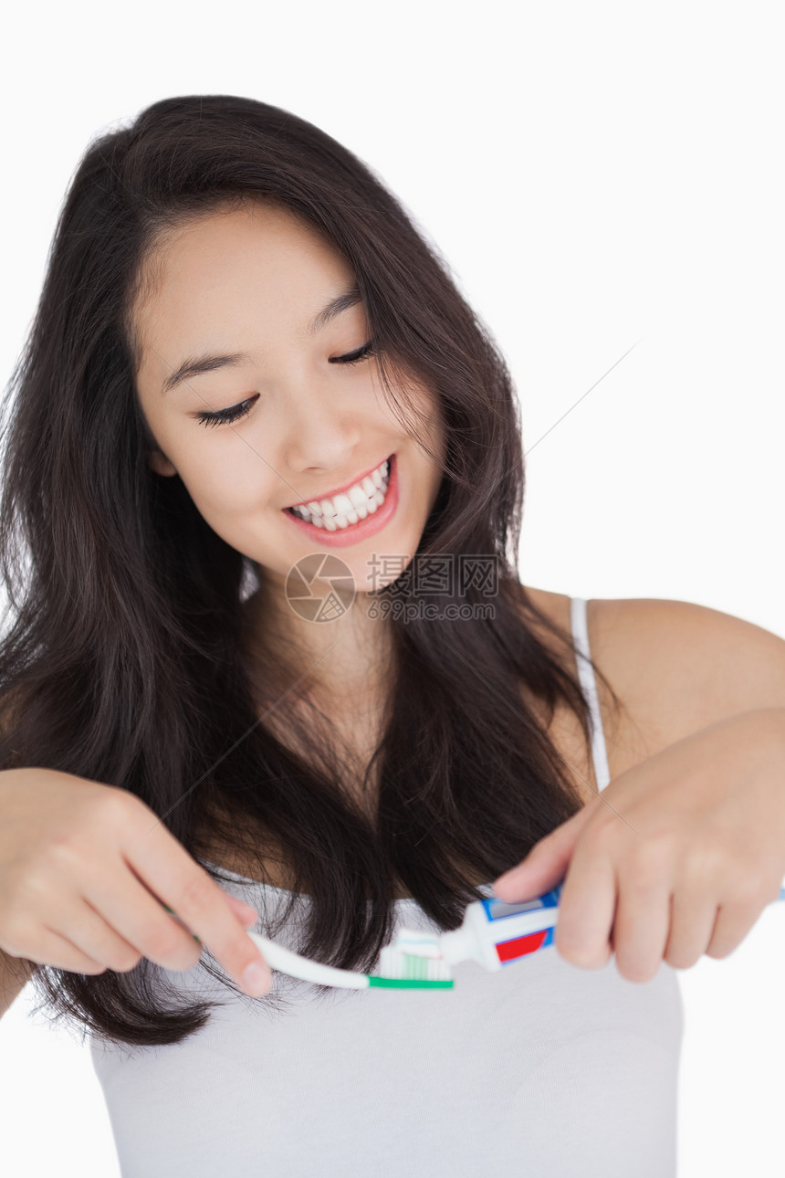 妇女带着牙刷和牙膏时笑着图片