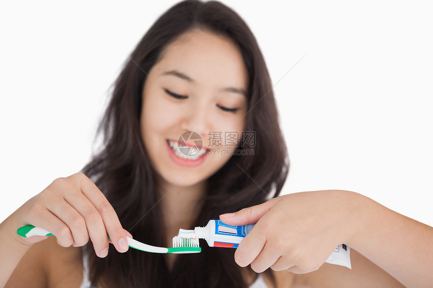 在牙刷上涂牙膏的女人棕色卫生黑发女性眼睛管子口腔牙齿微笑混血图片