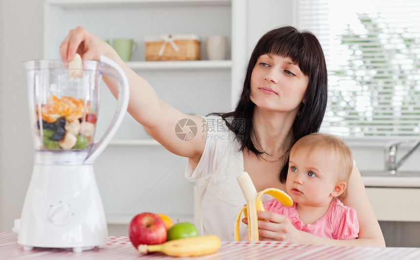 可爱的黑褐色女人 在香蕉里撒着香蕉边抱着孩子婴儿妈妈女性家庭生活厨房女孩食物幸福父母图片