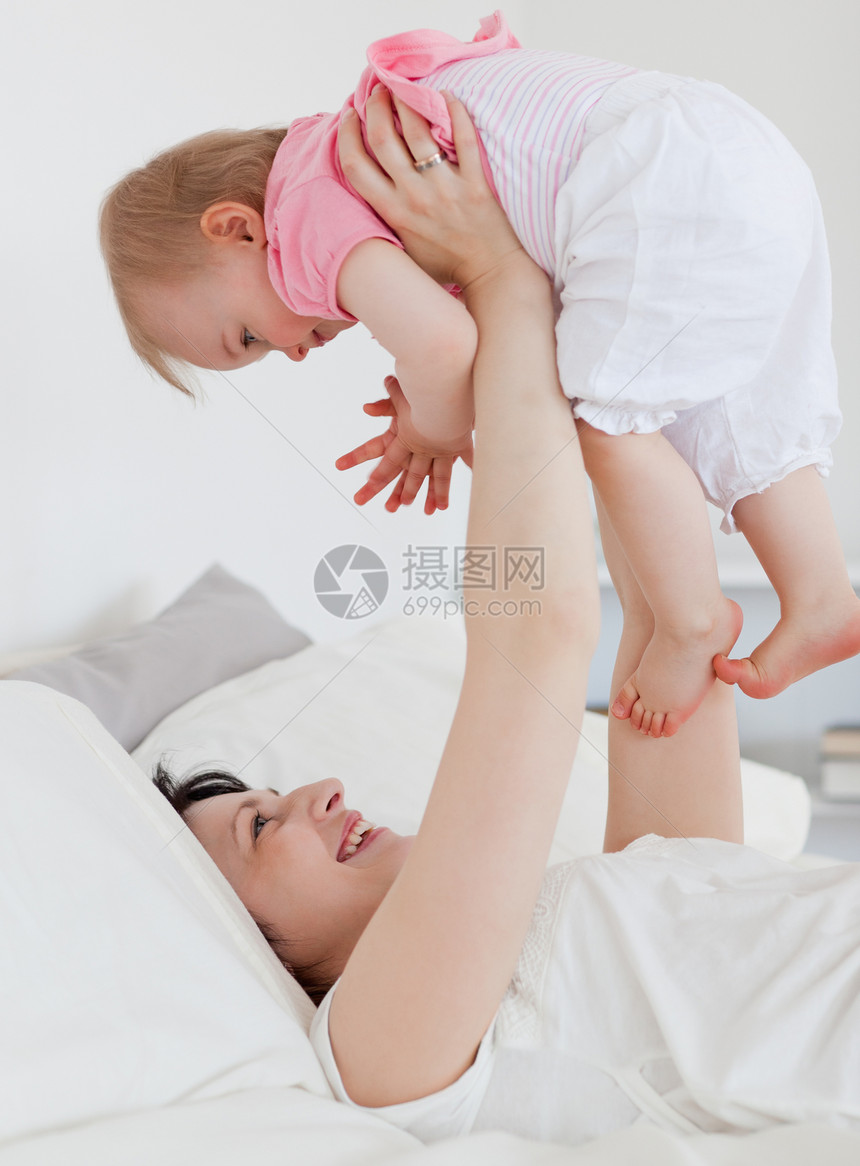 美丽的黑发美女在睡着时与婴儿玩耍图片