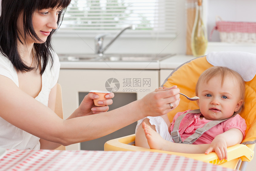 迷人的黑发女人在坐着喂婴儿图片