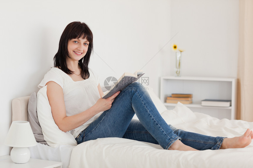 坐在床上看书的有魅力的黑褐色女人图片
