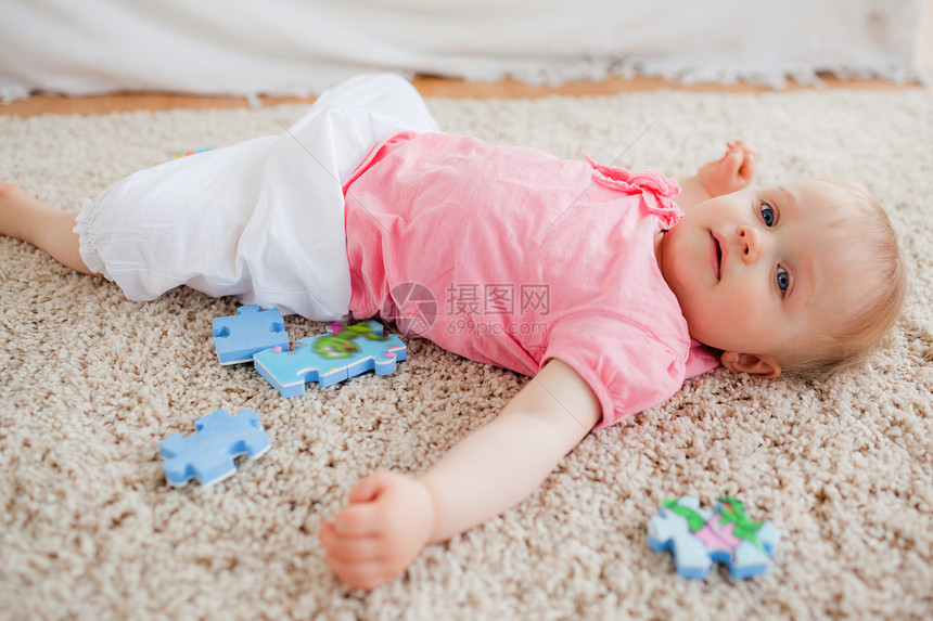 金发可爱的婴儿 玩着拼谜片 而躺在一头鲤鱼上图片