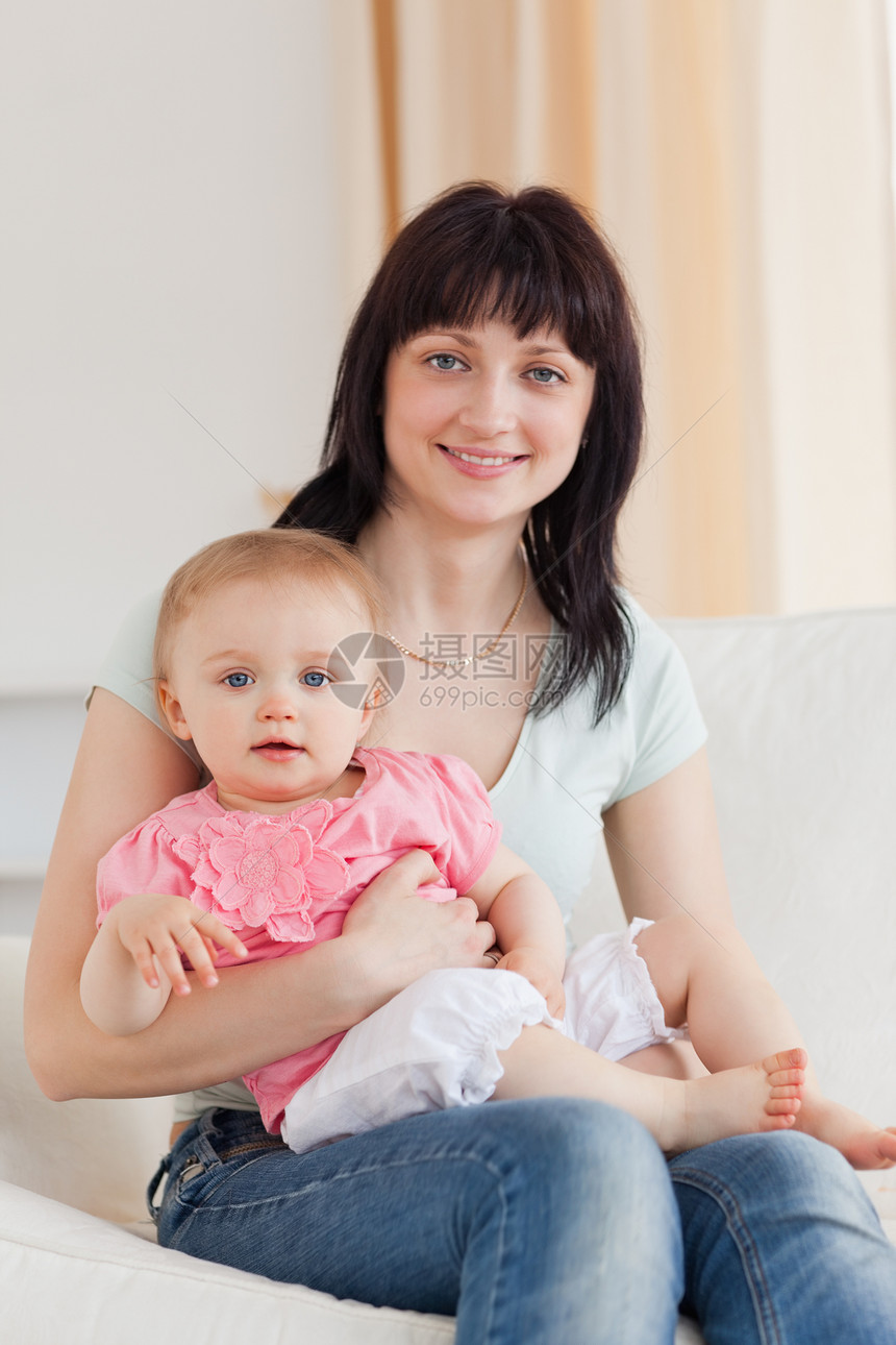 迷人的女士坐在一个S座上 抱着她的婴儿在她的怀里休息室妈妈父母孩子母亲房间生活女儿喜悦乐趣图片