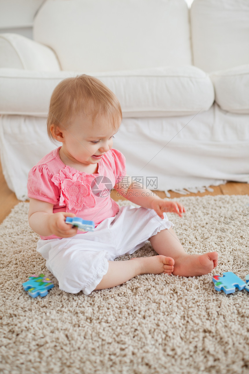 婴儿坐在地毯上时玩着拼图片游戏图片