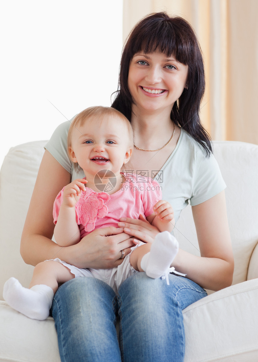 好漂亮的女人 抱着她的婴儿 在她的怀里 同时坐着图片