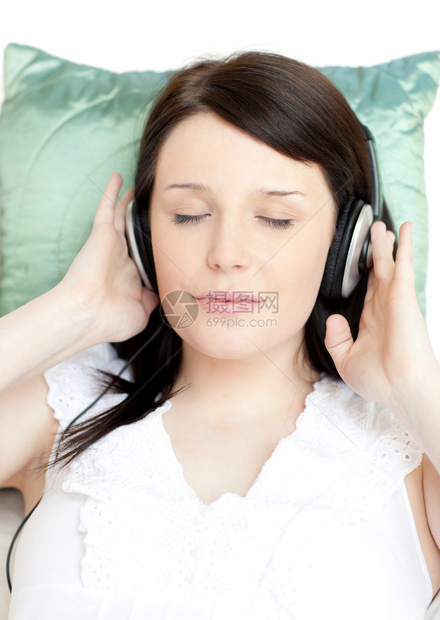 放松的年轻女子用耳机听音乐图片
