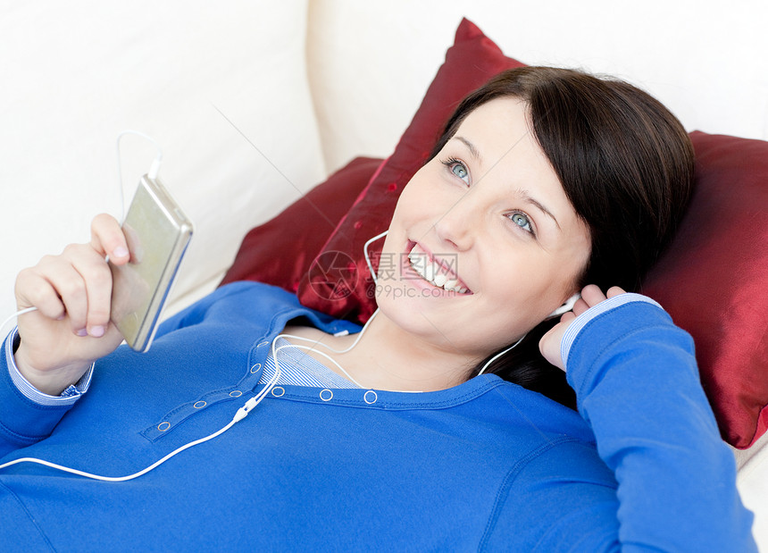 快乐的女士用耳机听音乐休息黑发长椅女性音乐微笑乐趣成人房间客厅图片