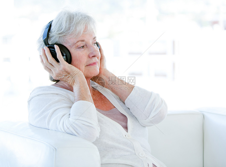 迷人的资深妇女用耳机听音乐图片