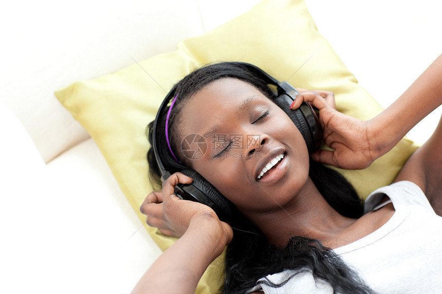 在沙发上躺着耳机听音乐的放松女性图片