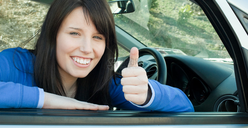 快乐的少女女孩 一个拇指举起一个拇指 坐在她的车里图片