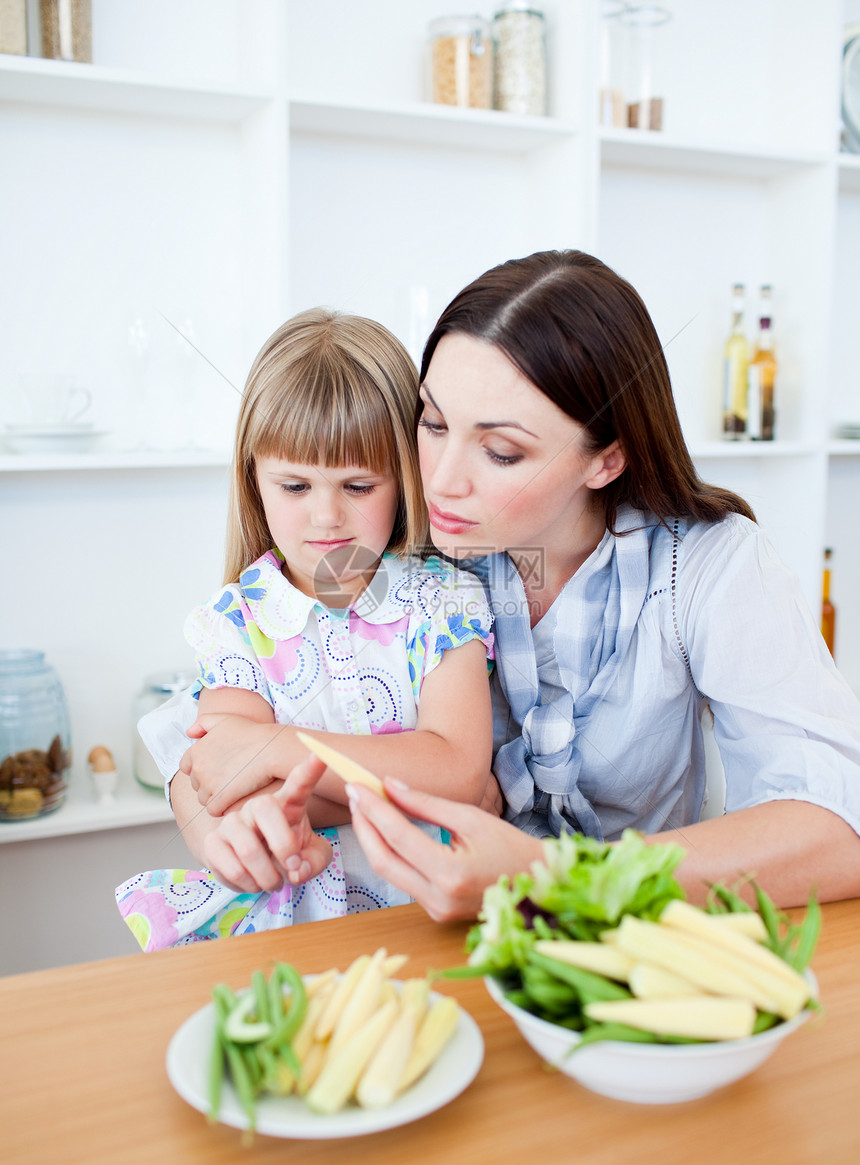 与母亲一起吃蔬菜的不满意小女孩和妈妈图片
