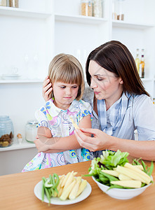 讨厌的金发金发女孩和母亲一起吃蔬菜背景图片