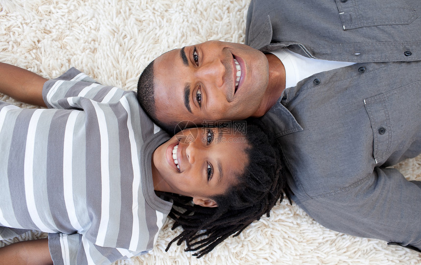 微笑的非裔美国父亲和儿子在地板上放松图片