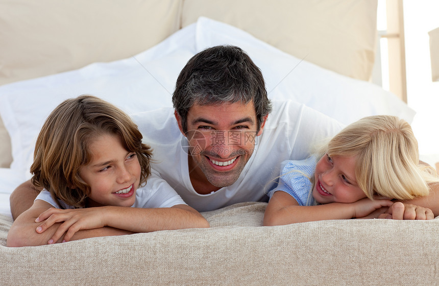 微笑的父亲和孩子躺在床上说话时 他的孩子躺在床上图片