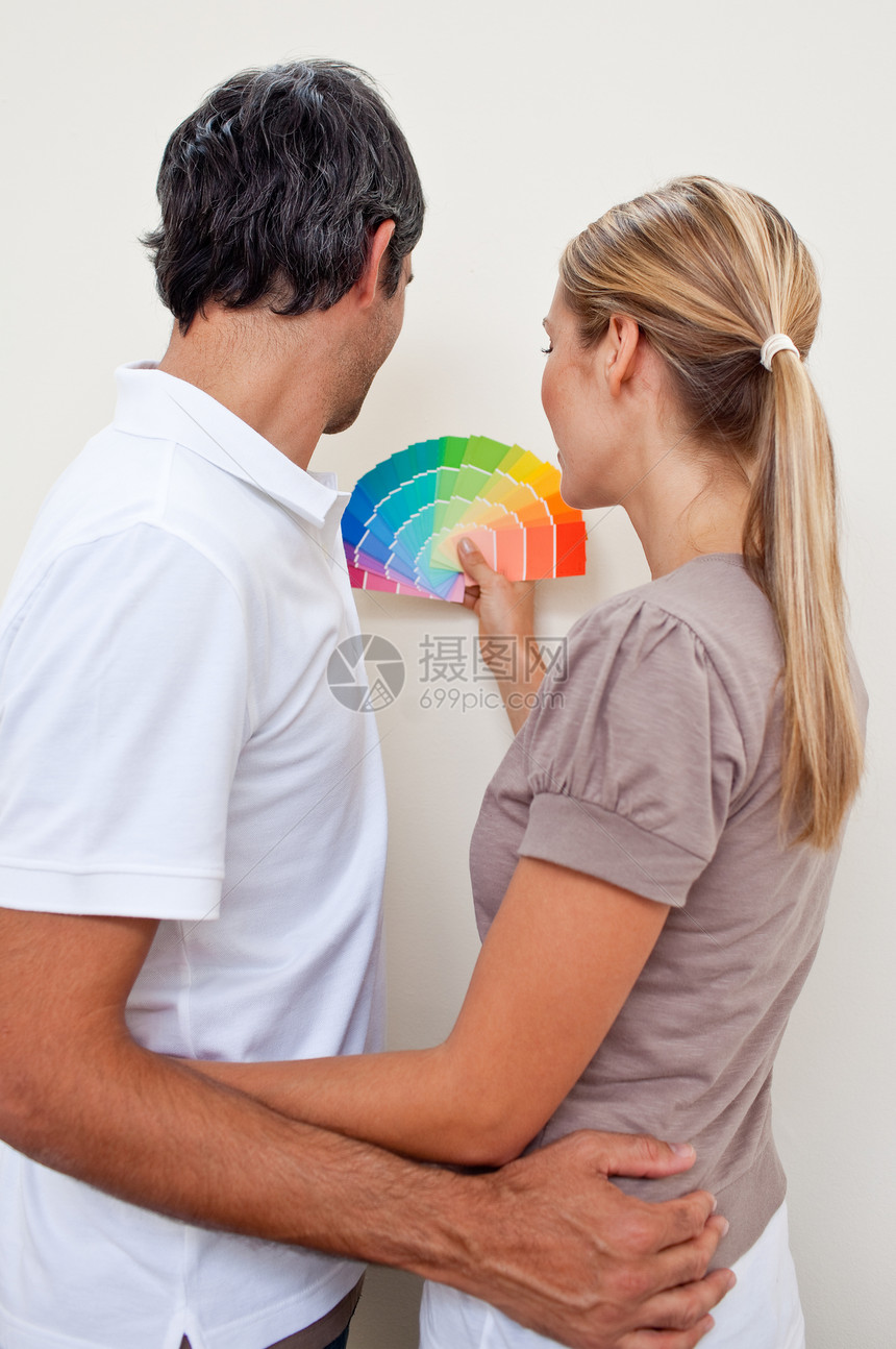 快乐的夫妇选择一个颜色 与油漆他们的卧室图片