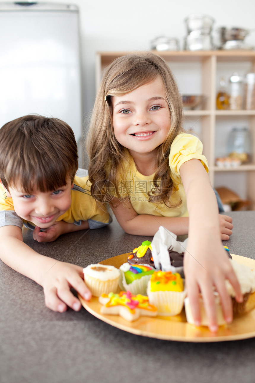哥哥和姐姐吃饼干女性童年烹饪微笑享受桌子后代儿子男生帮助图片