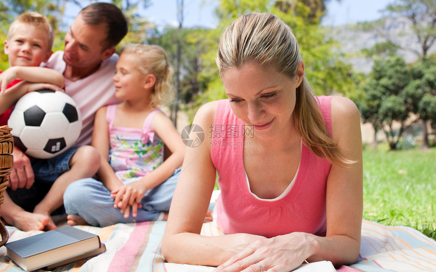 专注的母亲在野餐时和家人一起看书图片