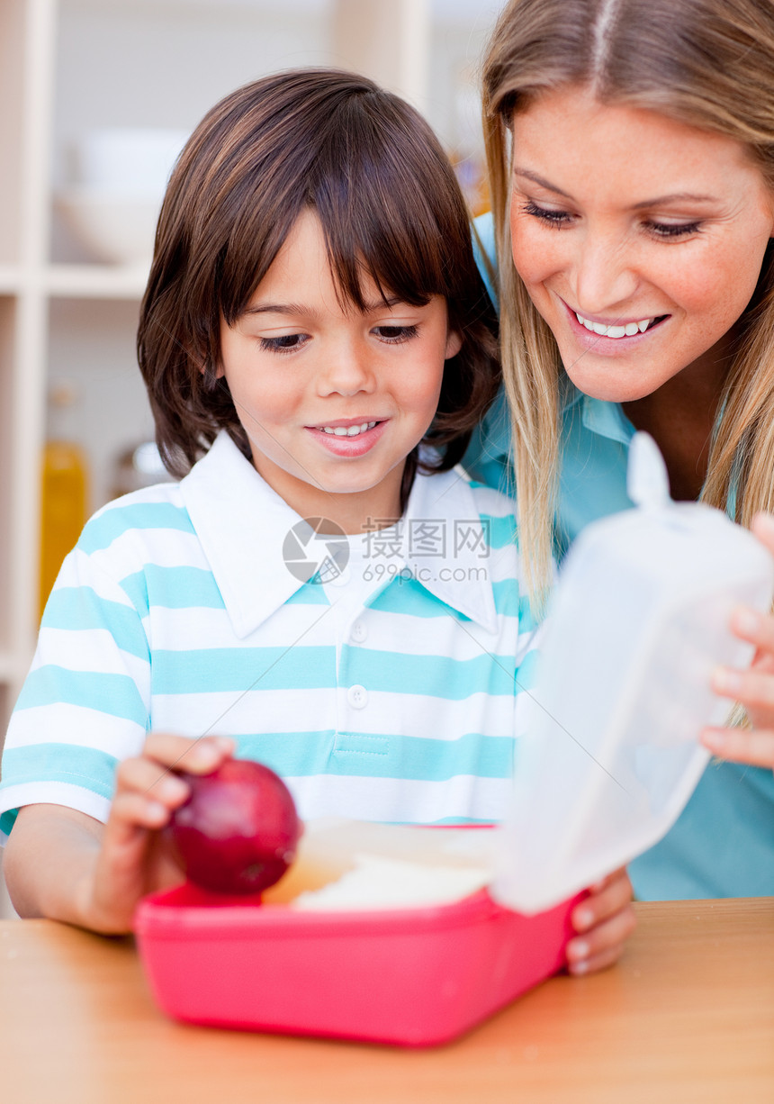 微笑的小男孩和他的母亲准备他的零食童年营养后代女性牛奶午餐水果男生厨房儿子图片