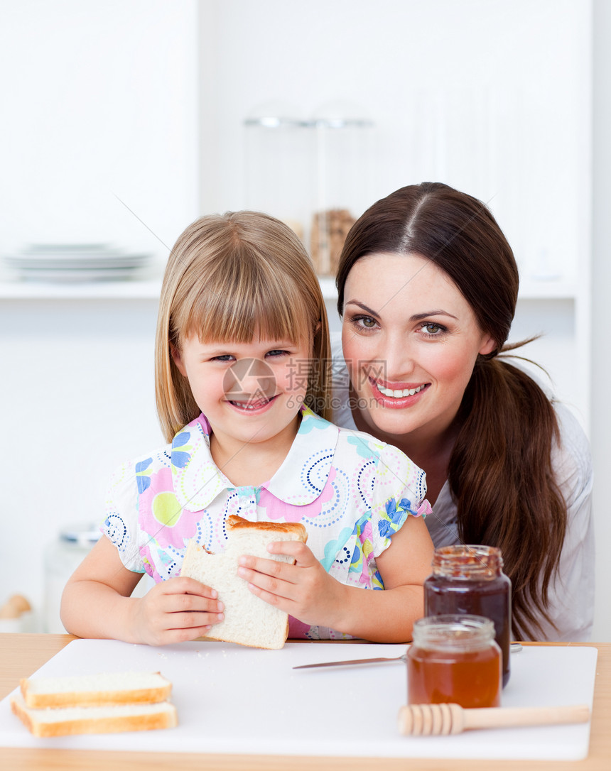 可爱的小女孩和她的母亲 吃着一小片面包图片