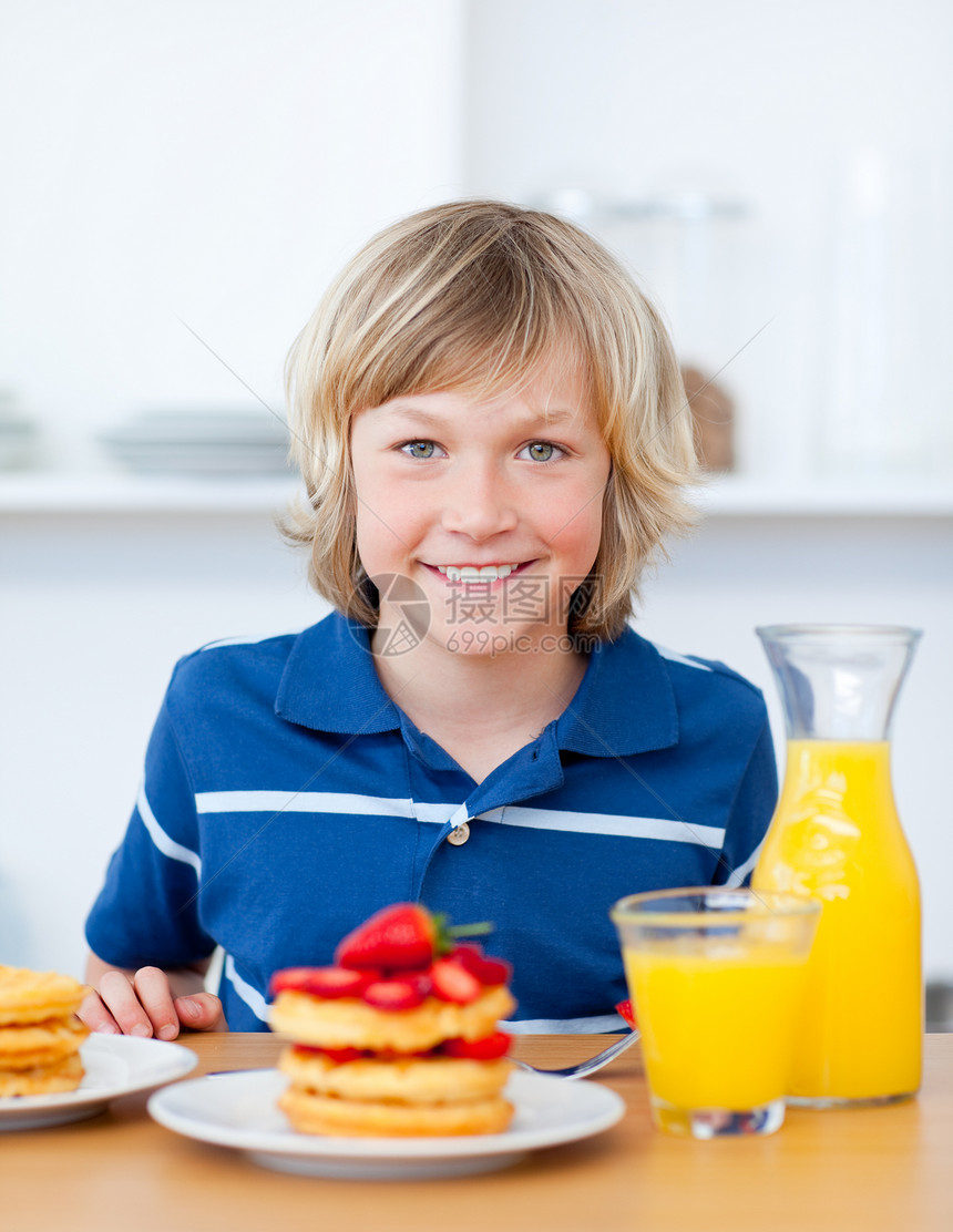 微笑的男孩用草莓吃华夫饼图片