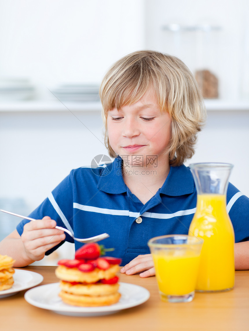 可爱的男孩用草莓吃华夫饼后代圆形橙汁微笑男性果汁快乐蛋糕幸福早餐图片